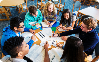 Students collaborating around a table with books and notes.