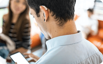 Man with wireless earbuds focused on a phone.